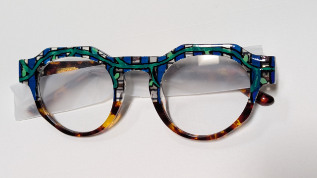 Tortoiseshell frames with a blue and green checker pattern and a vine crossing the brow